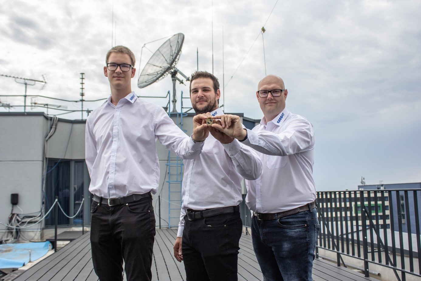 The developers with the panel on the roof of the Széchenyi István University, in the background the antenna with which they are preparing to receive the signals of the module to be placed on the satellite.